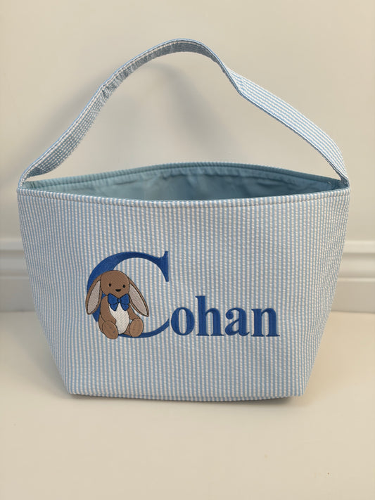 Blue checkered basket with embroidered bunny and name 'Cohan' on a beige background