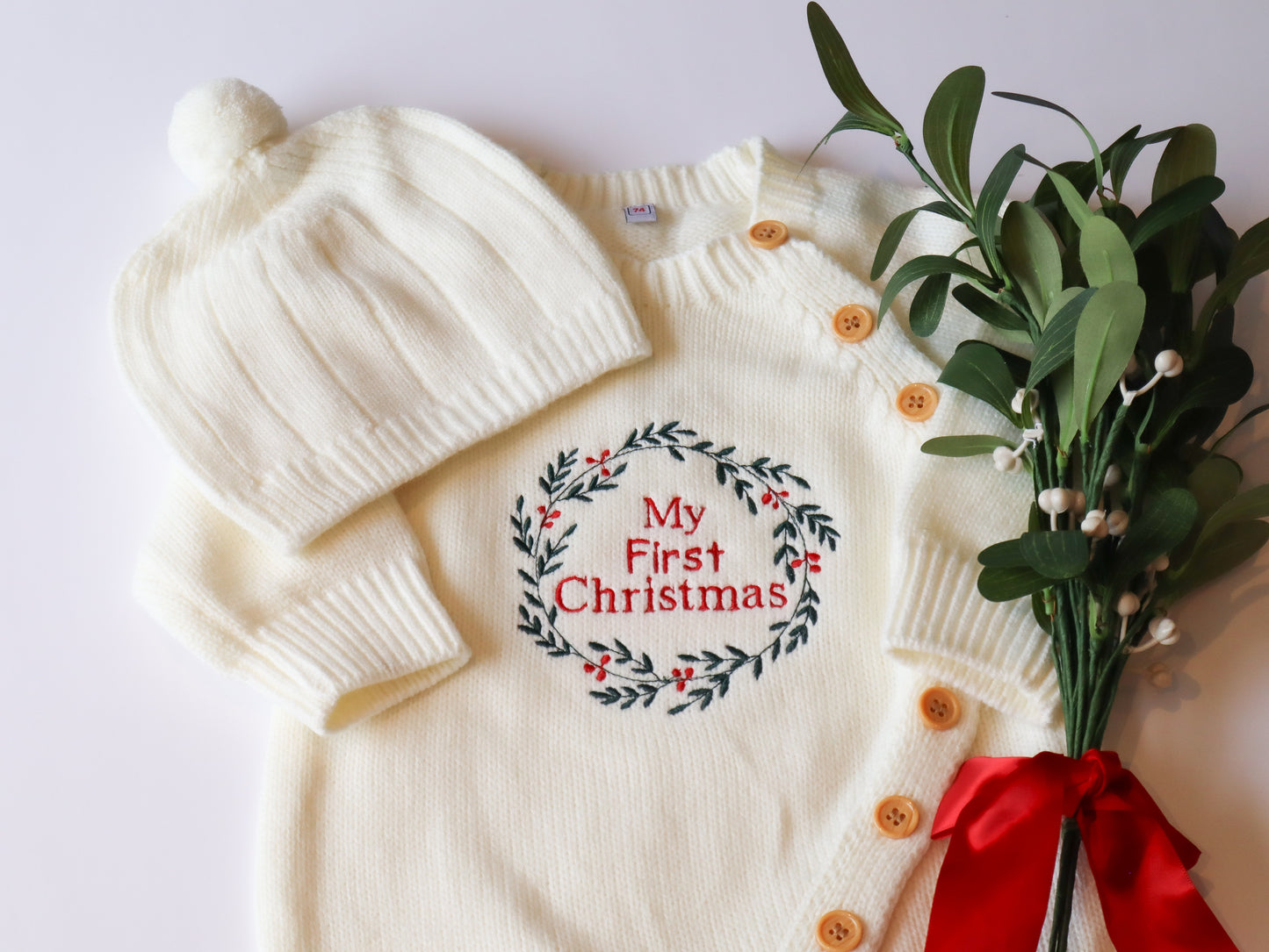 Baby Knit onesie with a wreath embroidery design with the words my first christmas