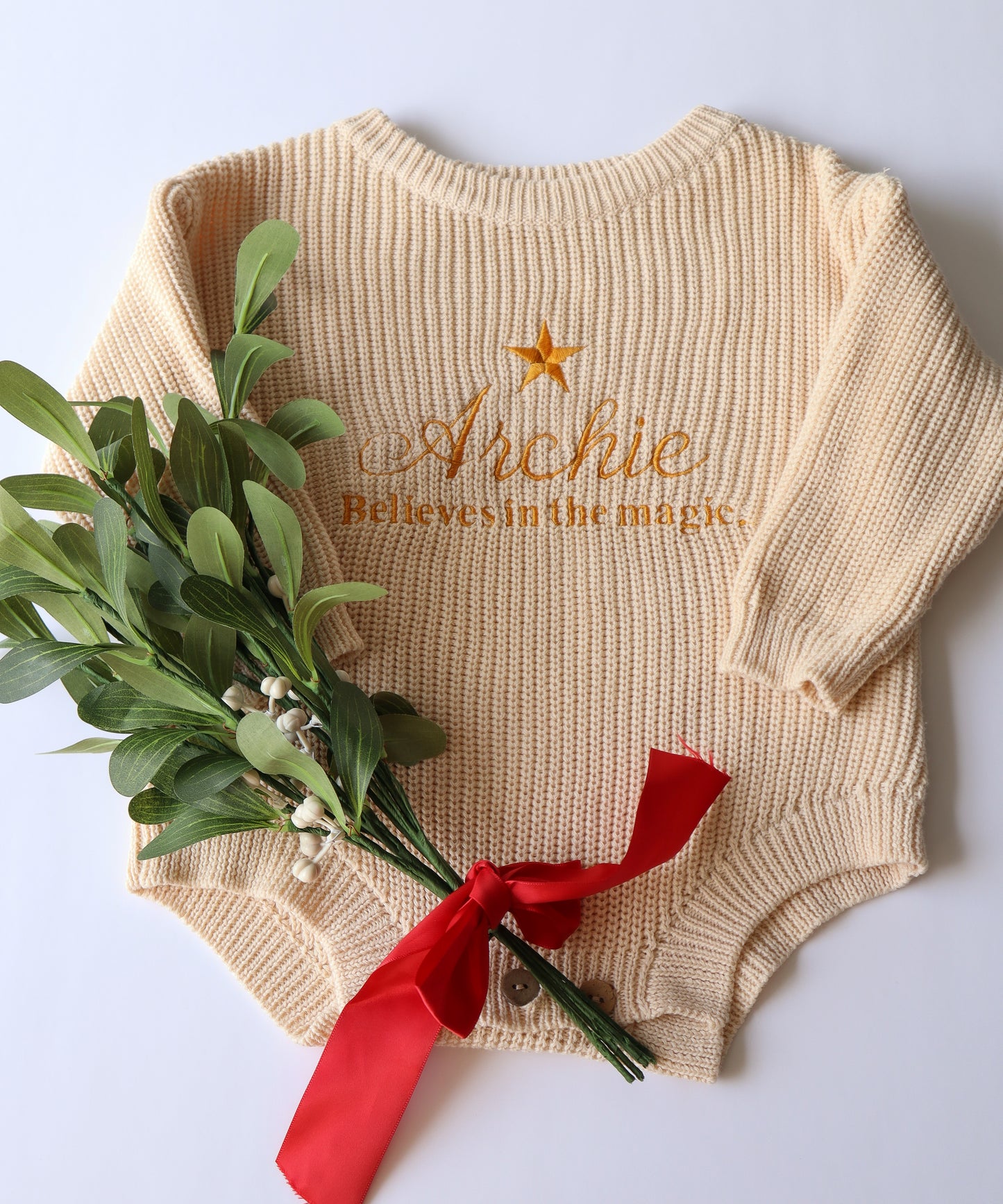 Beige Personalised baby romper with a star embroidery design with the words believes in the magic