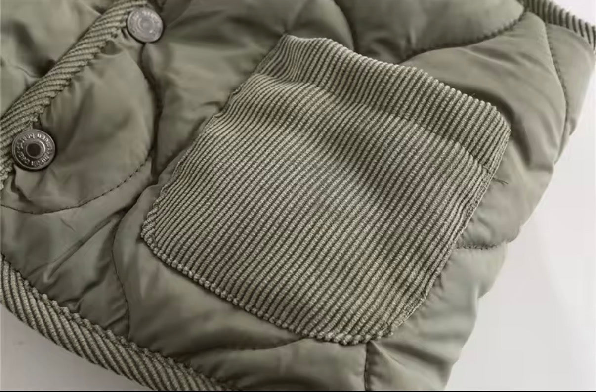 Close-up of a green puffer gilet with a textured patch on a light background