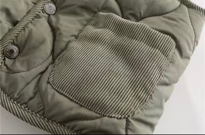 Close-up of a green puffer gilet with a textured patch on a light background