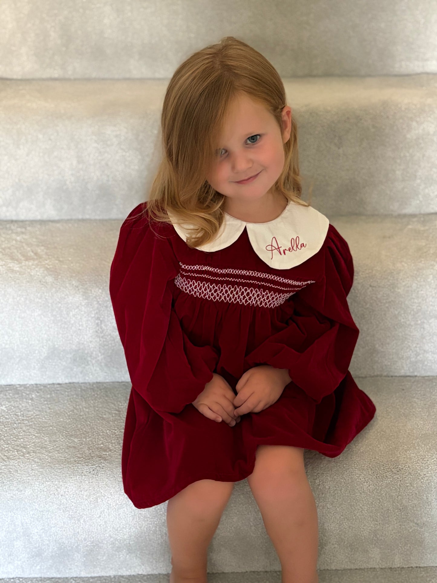 Girl with a red smocked dress embroidered on the collar 