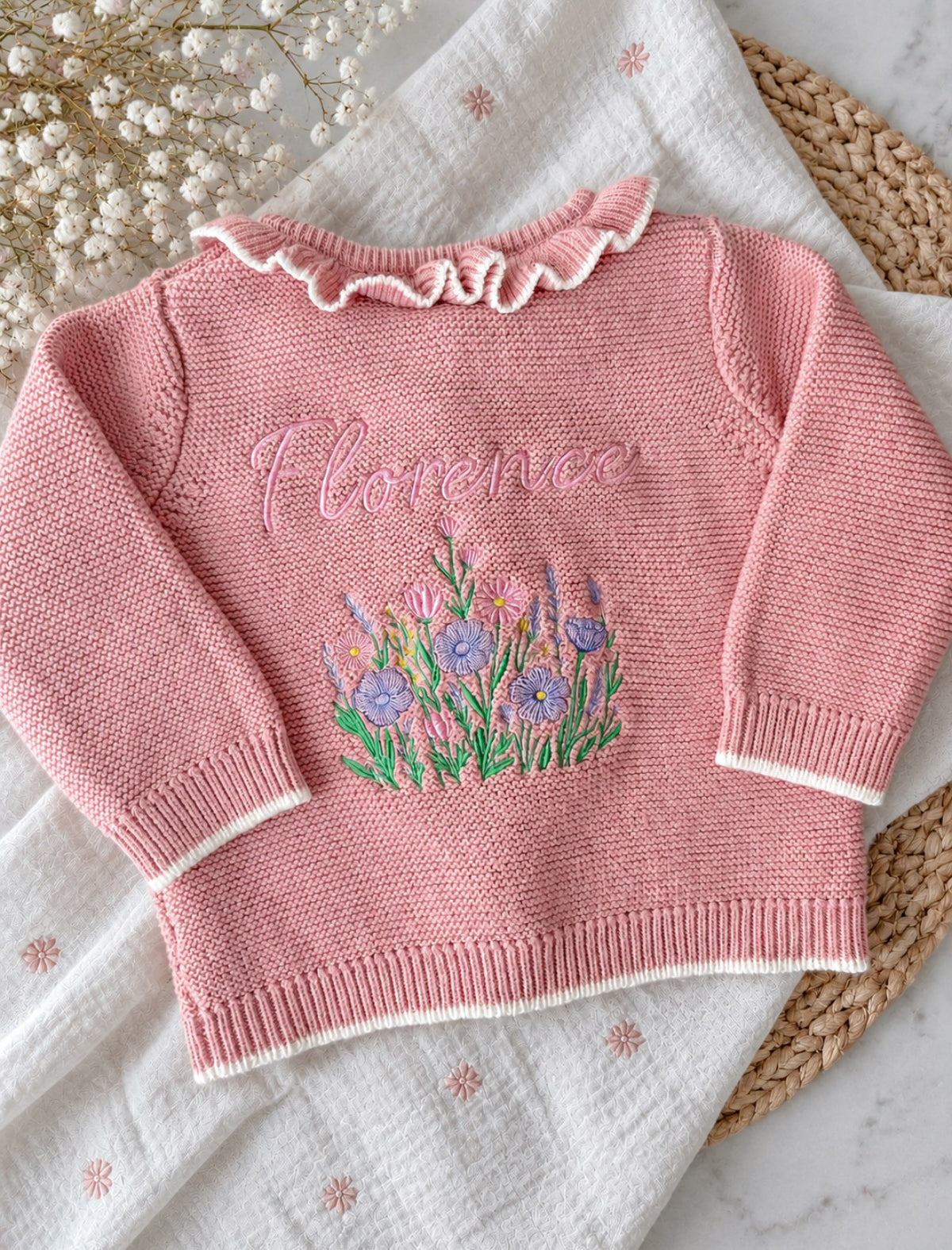 A pink cardigan embroidered with the name florence and a floral design 