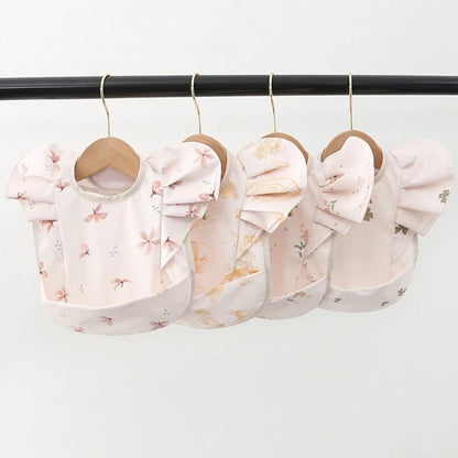 A set of three pink and floral patterned waterproof wing babies hanging on a rack.