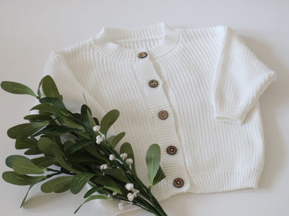 White ribbed cardigan with brown buttons on a white background 