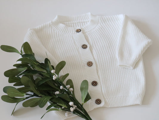 White ribbed cardigan with brown buttons on a white background 