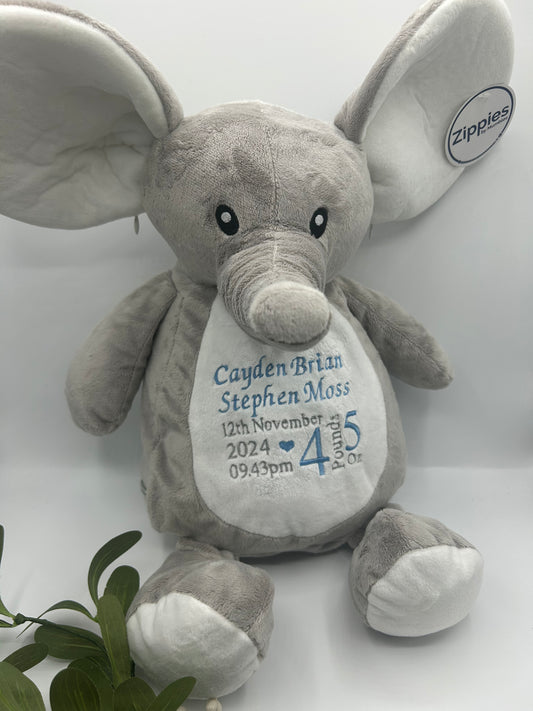 A gray Mumbles Zippie Birth Teddy with custom embroidery on its tummy, featuring babies full name, birthday, birth time and weight