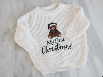 White sweater with a teddy bear and 'My first Christmas' text on a marble surface