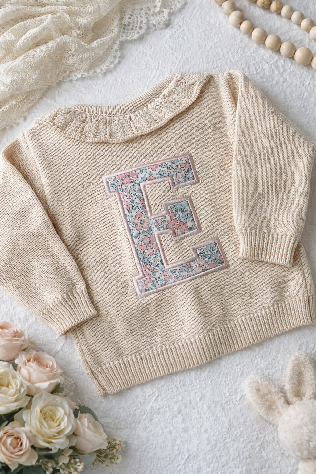 A beige cardigan with a frill collar and an initial E embroidered using a liberty of london fabric 