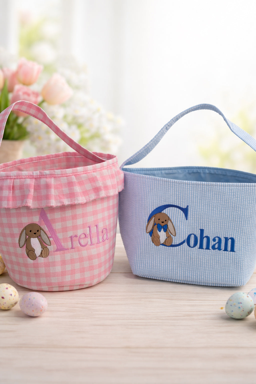 Two Easter baskets, one pink and one blue, with embroidered names and bunny designs on a light background.