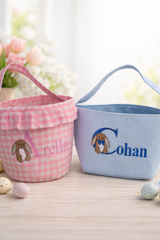 Two Easter baskets, one pink and one blue, with embroidered names and bunny designs on a light background.