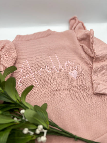 A pink knit cardigan with name embroidered on the back and hearts 