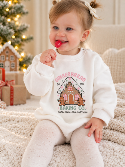 a girl wearing a white fleece romper with a cute gingerbread design embroidered on